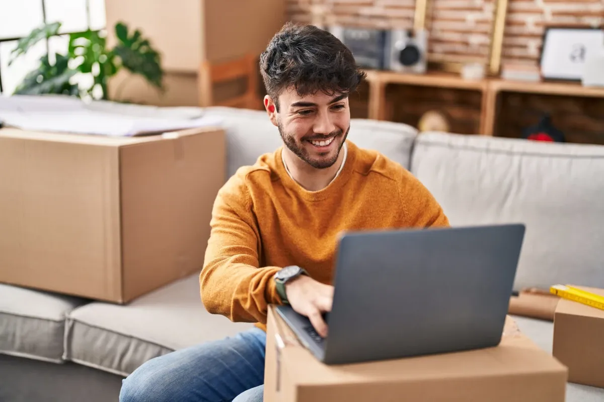 Man works on laptop ontop of moving boxes