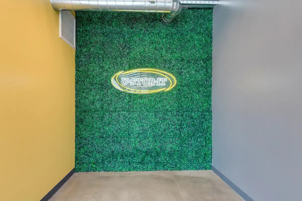 U-Stor-It facility feature wall decorated with artificial greenery and a central branded logo.
