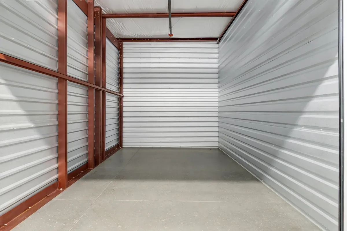 Interior of a clean, empty self-storage unit with corrugated metal walls and concrete floor.