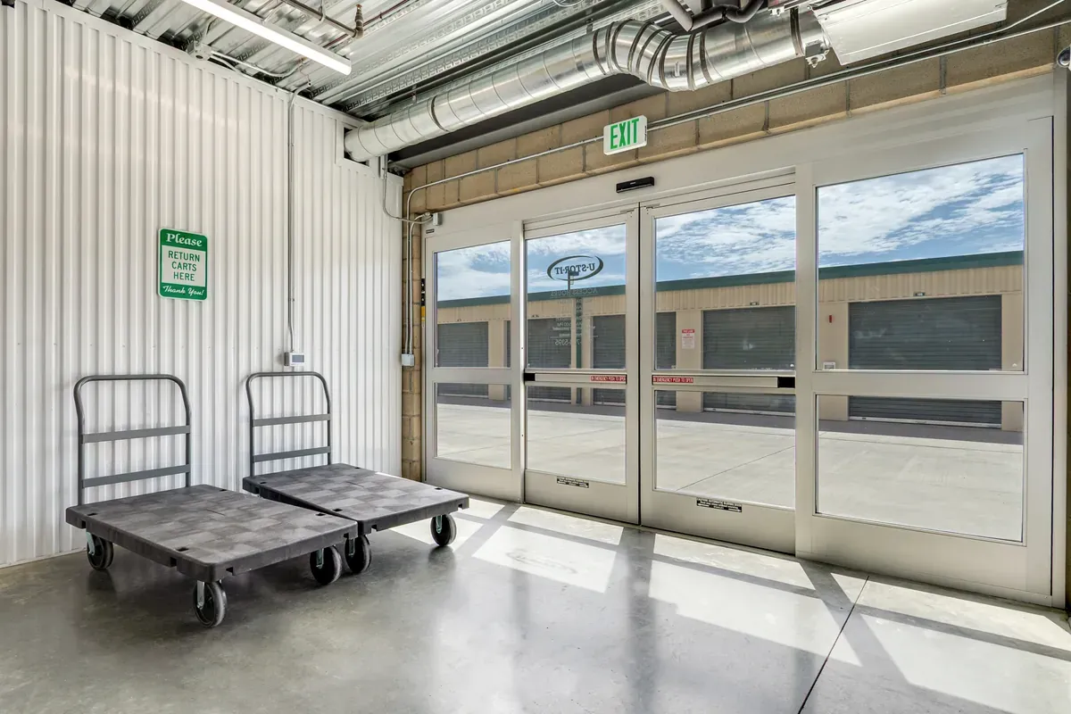 Automatic sliding glass exit doors inside a self-storage facility with flatbed push carts available nearby.