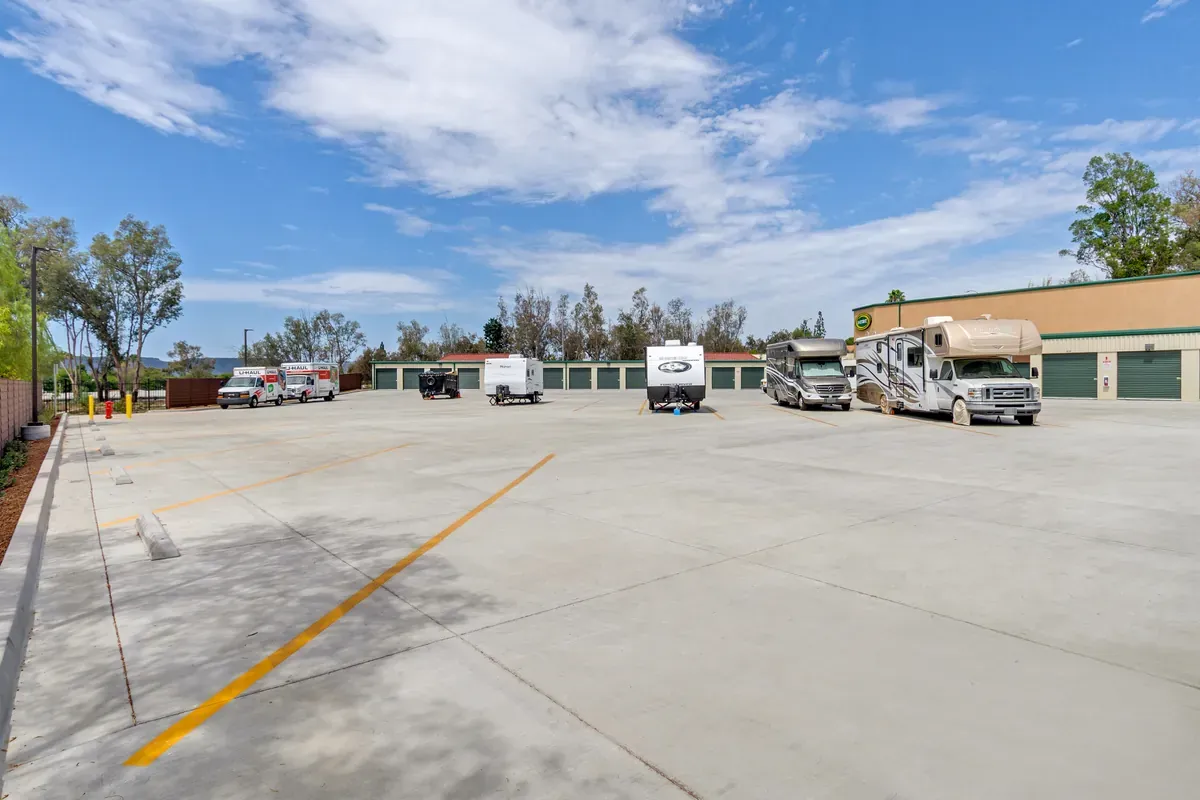 Outdoor RV and boat storage parking lot with travel trailers parked in lined concrete spaces under a blue sky.