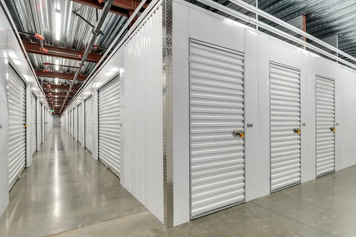 Indoor climate-controlled self-storage units with white roll-up doors along a polished concrete floor.